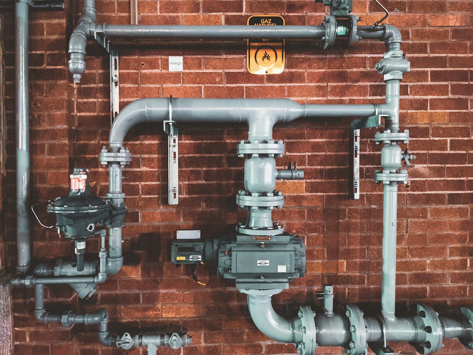 Industrial pipework and valves on a brick wall